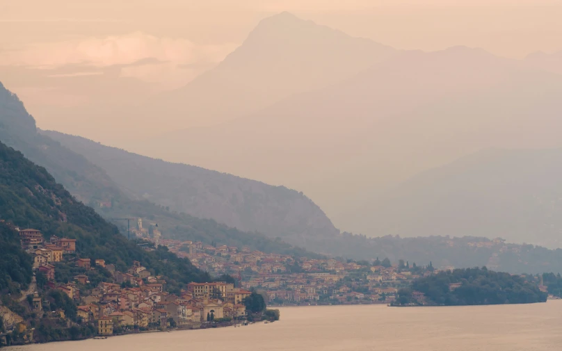 a body of water with some houses on the hillside behind it