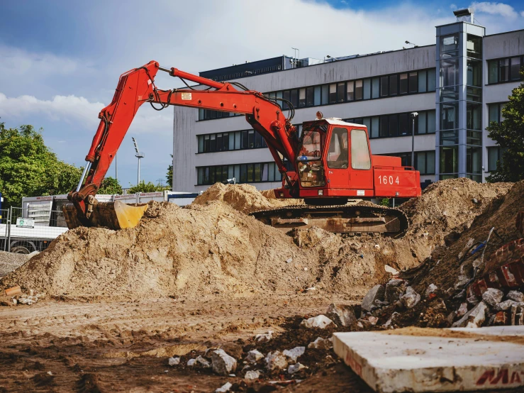 a large orange digger on top of some dirt