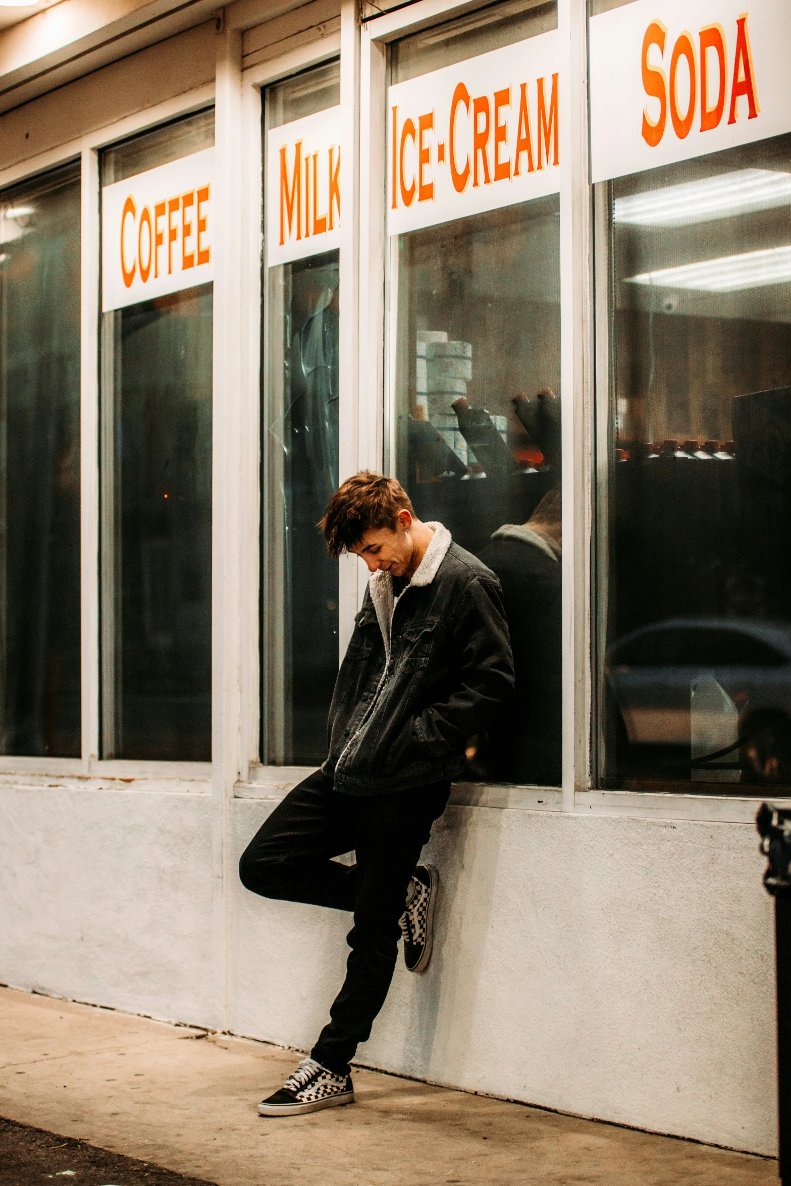 a person leaning against a window with the word ice cream on it