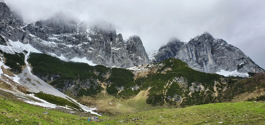 a grassy hill in front of large mountains