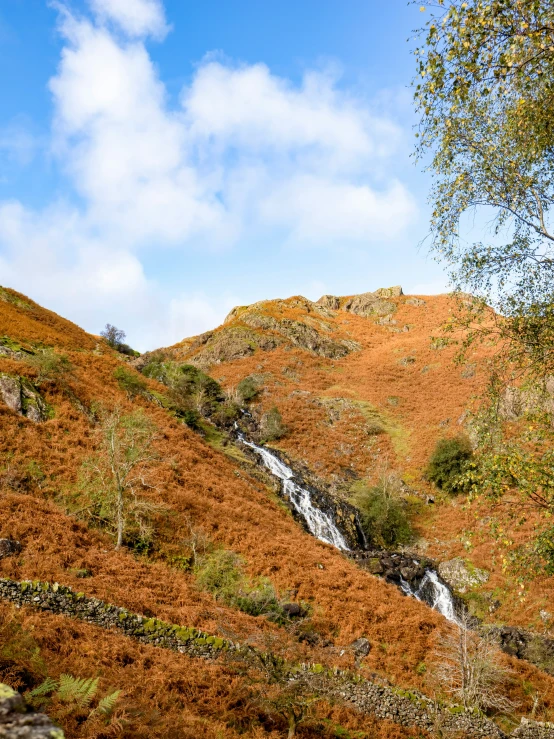 a waterfall flowing into an orange hillside under a blue sky