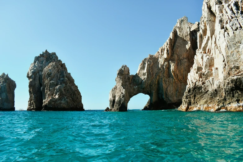 several rocks near the ocean with clear blue water