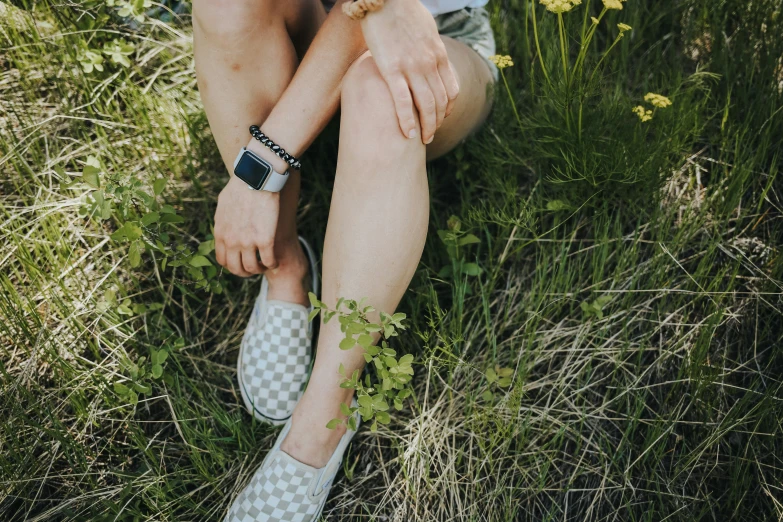 a woman is sitting in the grass wearing blue and white shoes