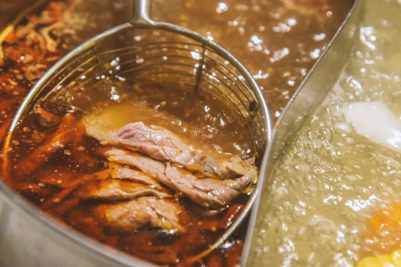 a metal bowl with soup being cooked on a stove