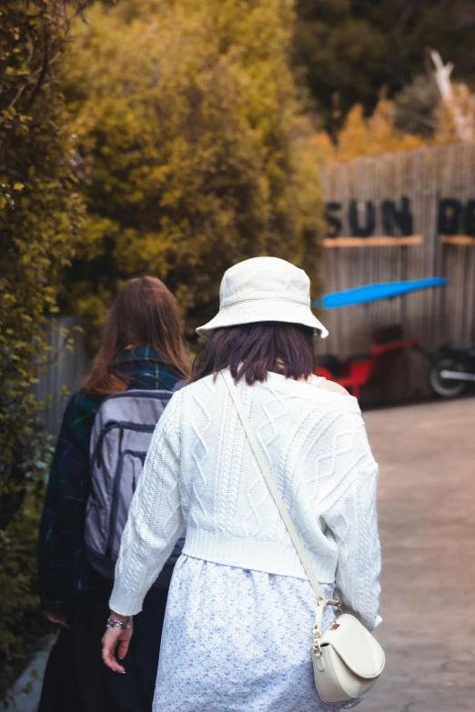 two people walking on sidewalk with luggage