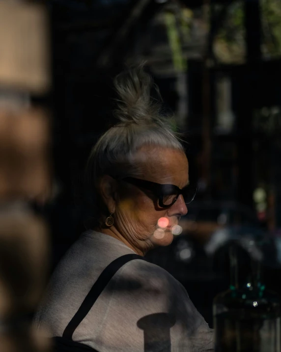 an old woman wearing sunglasses smoking cigarette in a city