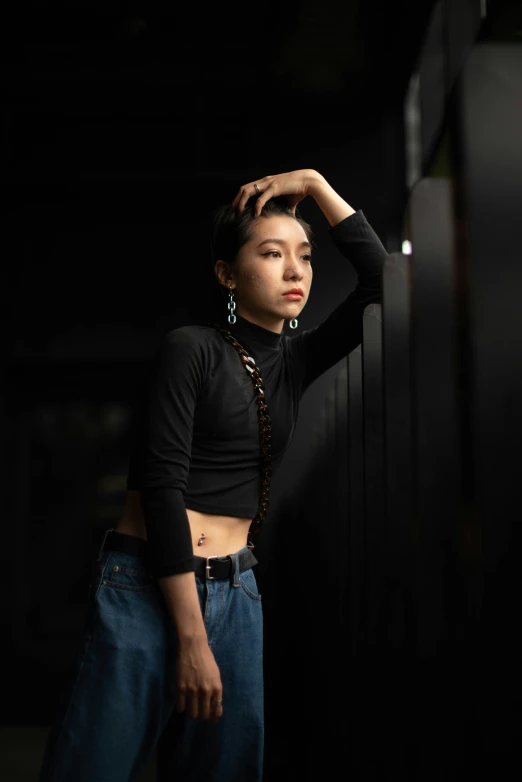 a woman in black shirt leaning against fence with black background