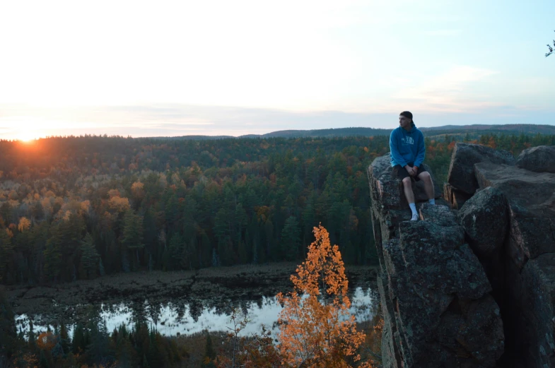 a woman sitting on top of rocks by a forest