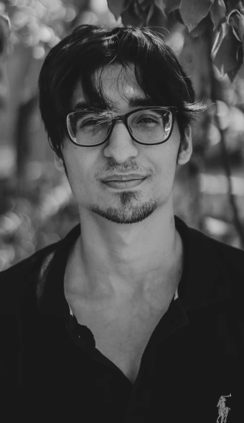 a man wearing glasses in front of a tree