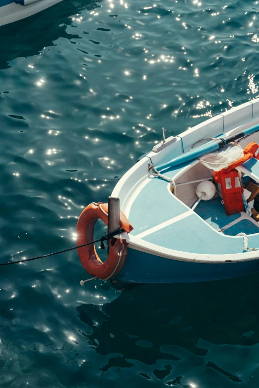 small blue boat floating on top of the ocean