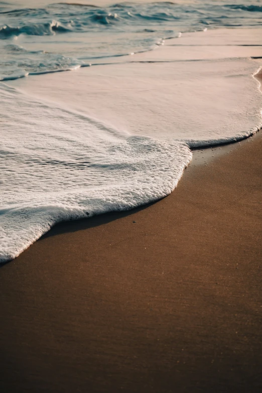 a brown beach with waves rolling in and out