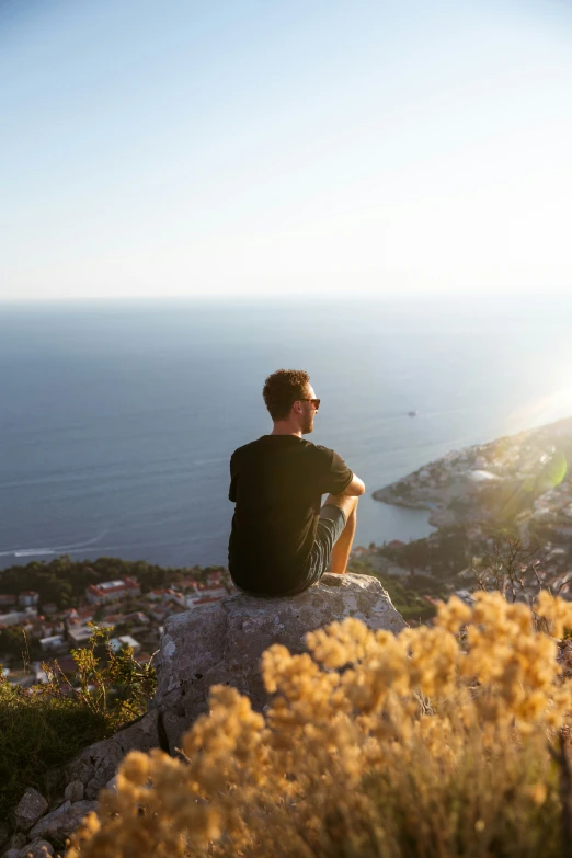 a young man sits on top of a cliff