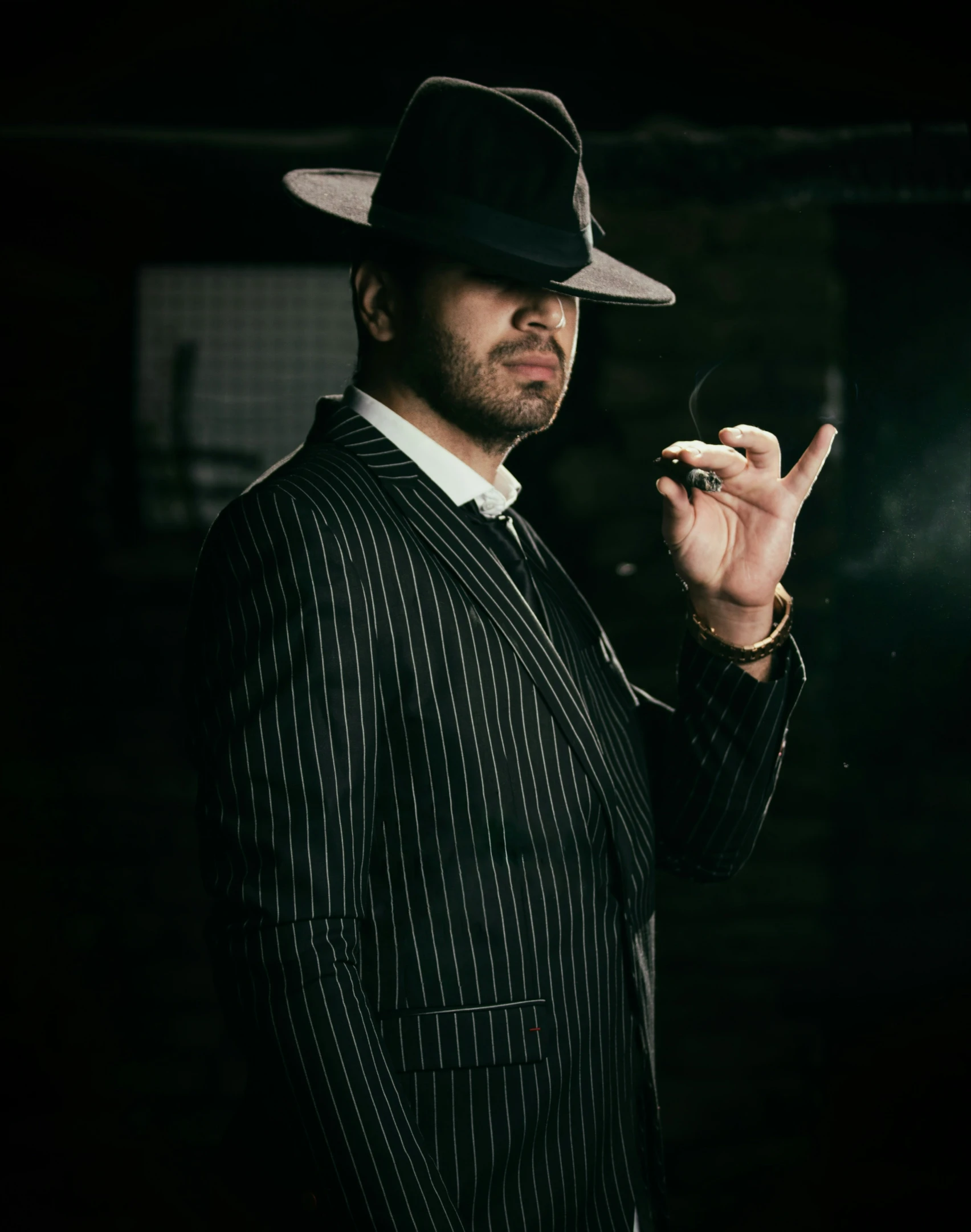 a man in a pinstripe suit and hat holding a cigarette