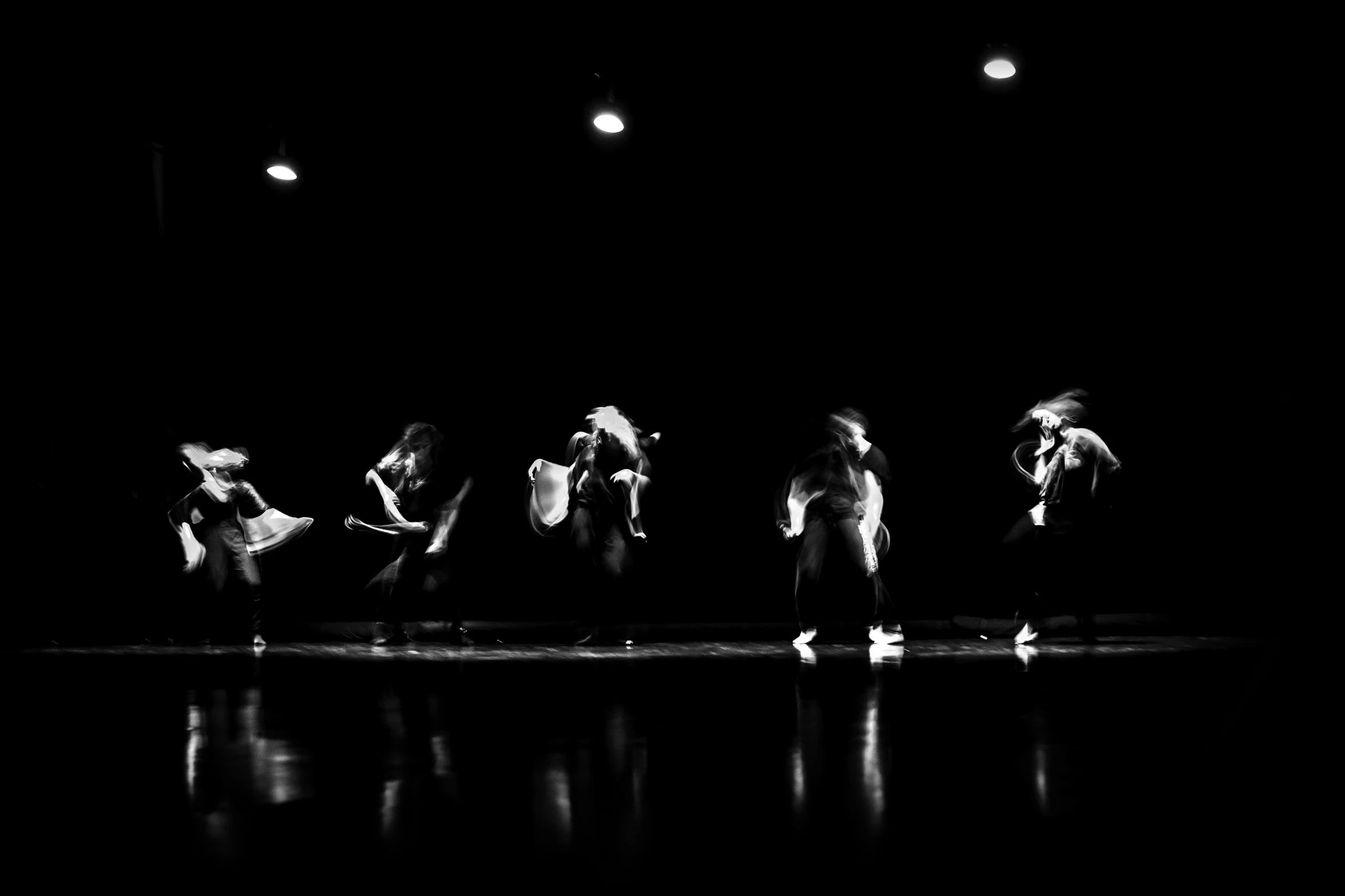 four dancers are on the stage with lights in the dark