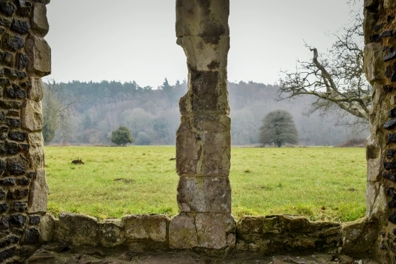 a window in an old building overlooking a green pasture