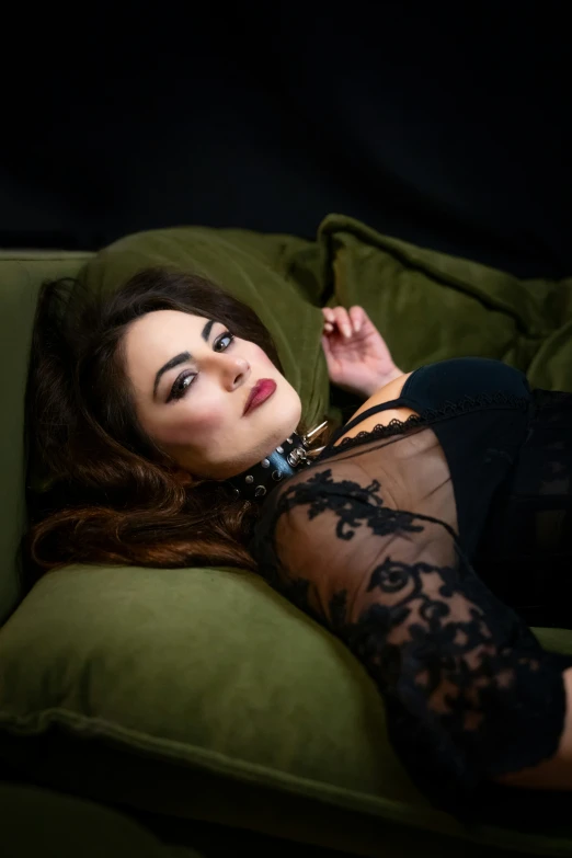 a woman in black lace and sheer dress laying on couch