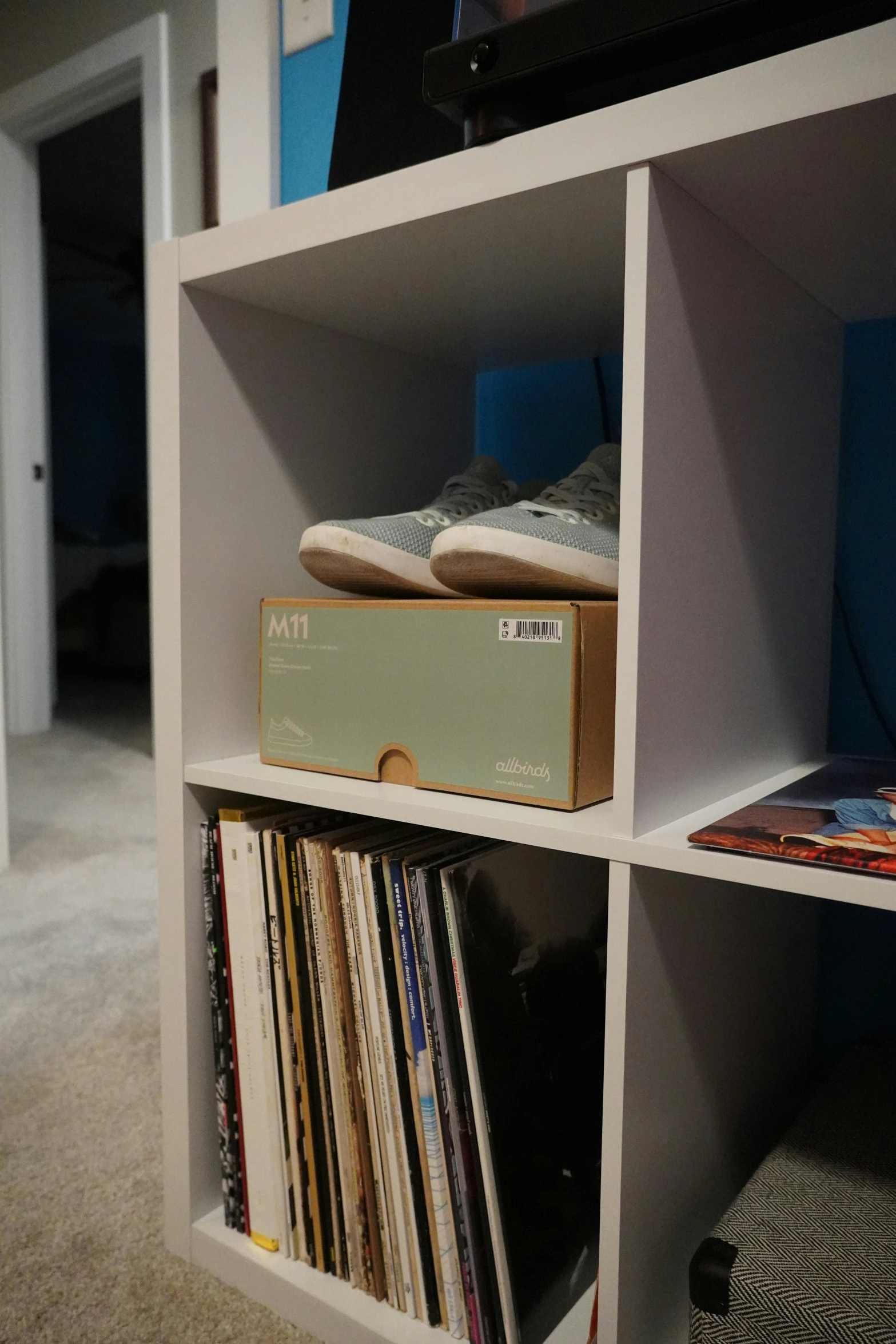 some records and a box sit on top of a shelf