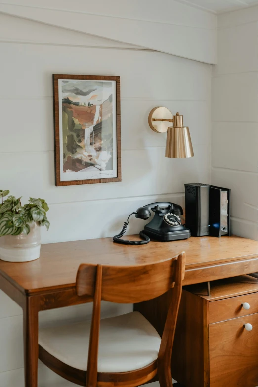 there is a wood desk with a phone and a chair