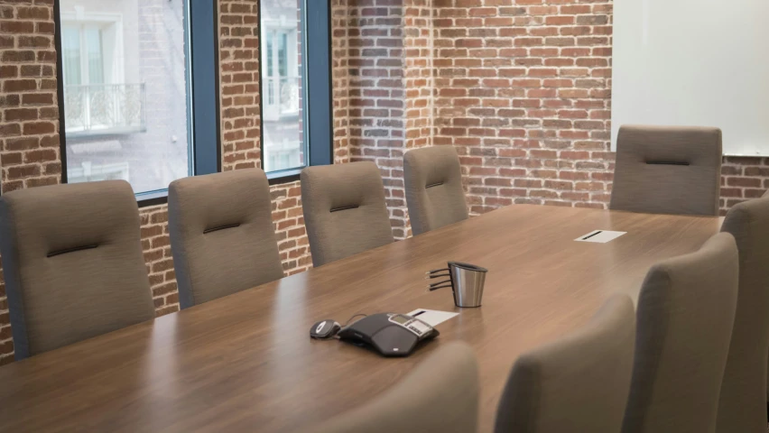 a wooden conference table and chairs with phone and camera on it