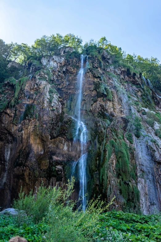 an extreme waterfall in a rocky mountain under a blue sky