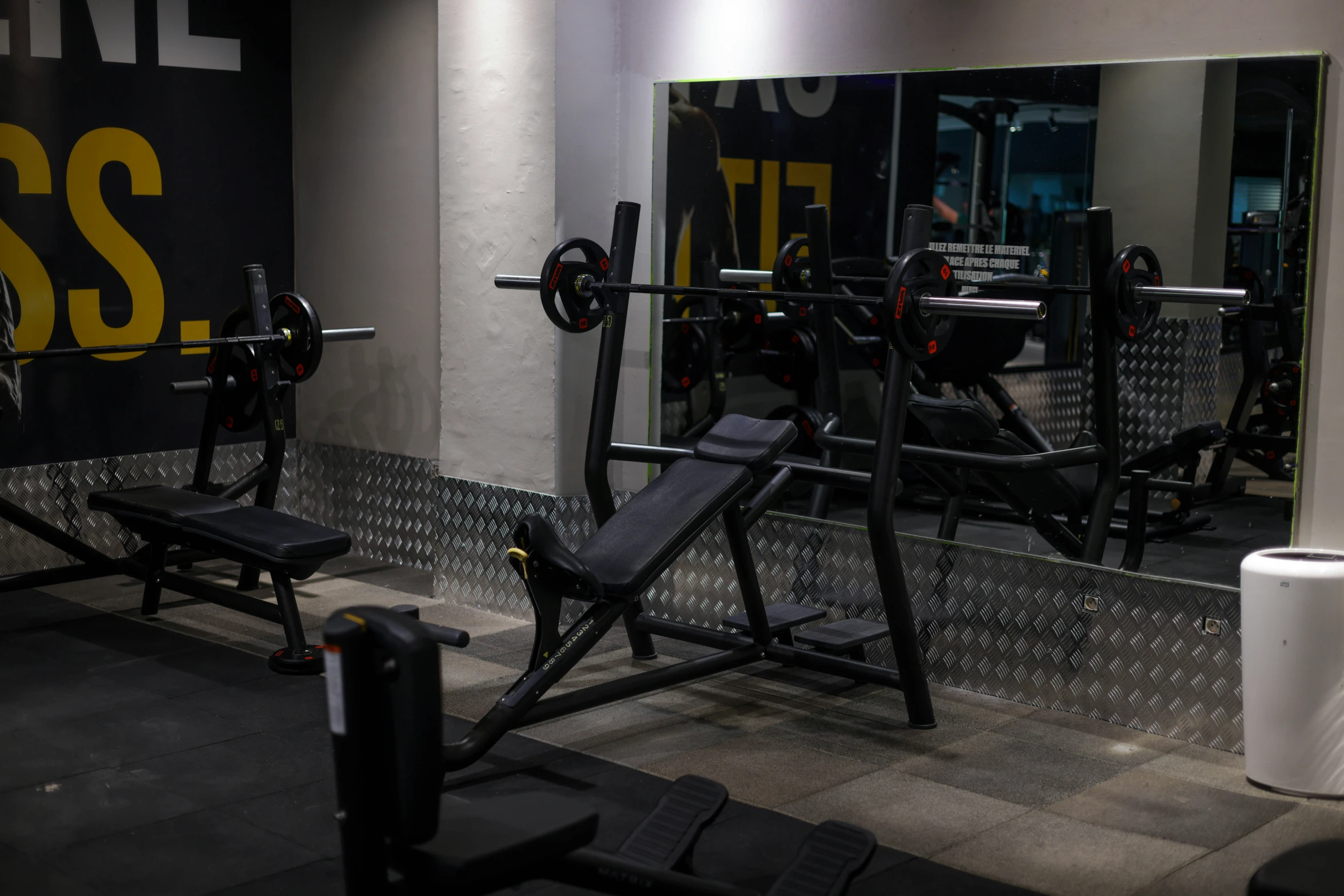 the weight bench sits in front of the mirror and other equipment