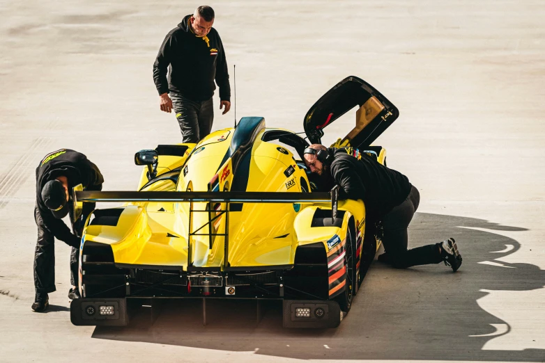 a racing car with people looking at it on the ground