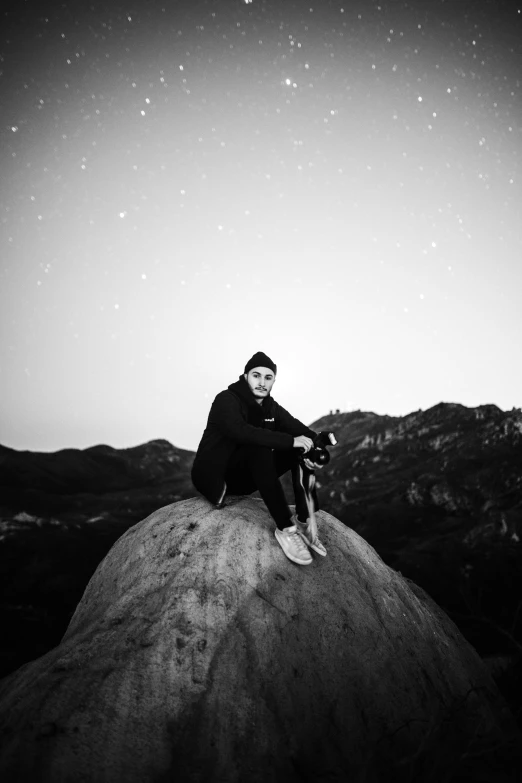 the man is sitting on the rock and posing