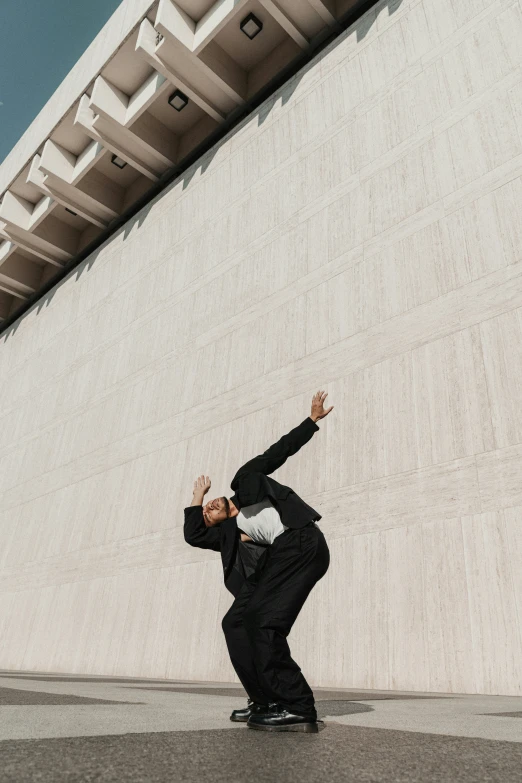 a man wearing a black suit stands in front of a building