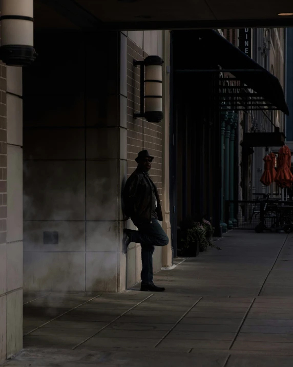 a man leaning on a building, waiting for someone to leave