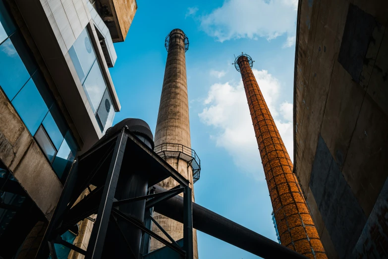 two tall chimneys stand behind a glass building