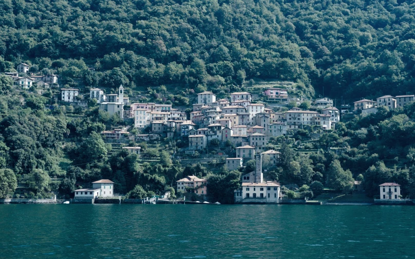 the view of a small village with several buildings on the shore of a lake