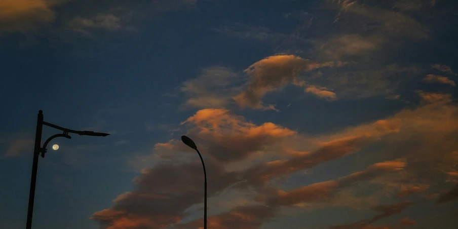 the view from below a street light with some clouds in the background