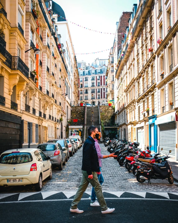 man walking across crosswalk in between two buildings