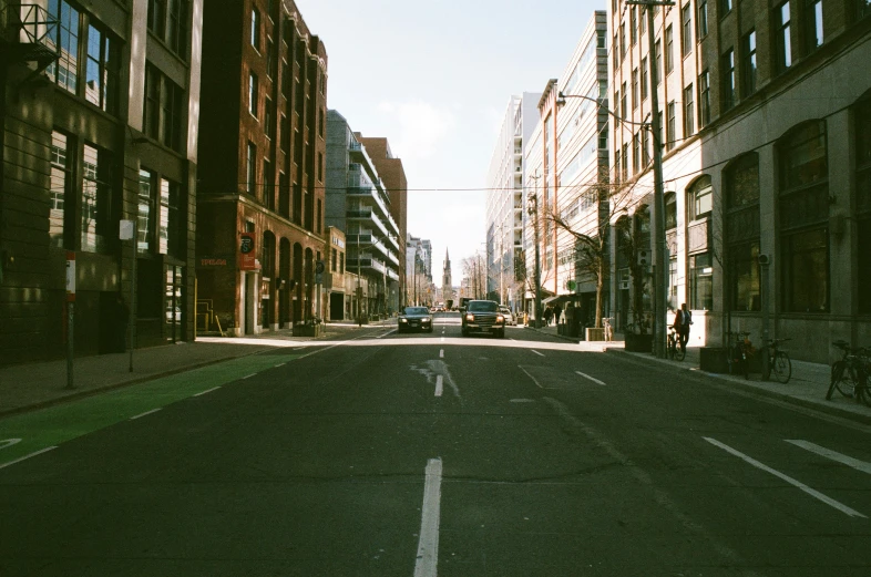 cars driving on a city street with tall buildings