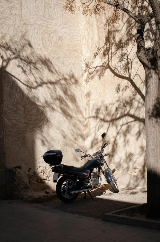 a motorcycle is parked by a wall with the shade cast on it