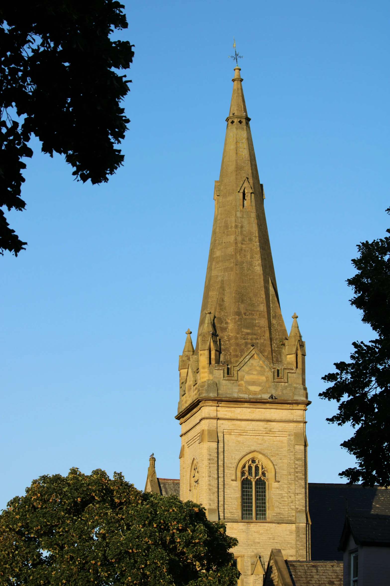 a tall clock tower with a weather vane on top of it