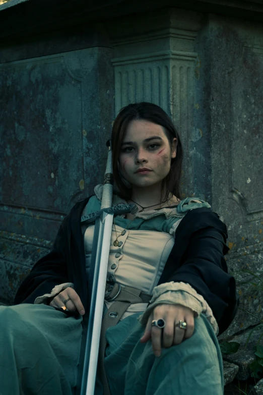 a woman in an old fashion outfit sitting holding a sword