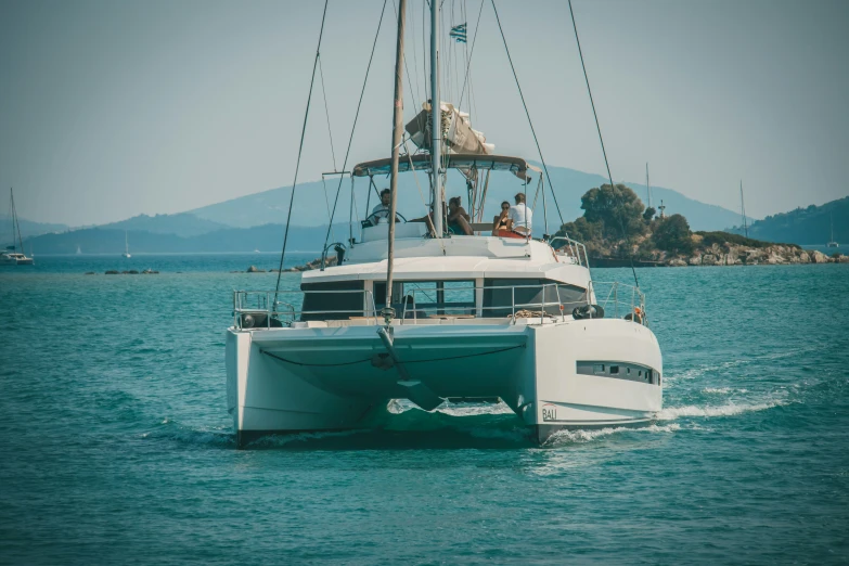 a white boat out in the ocean with people on it