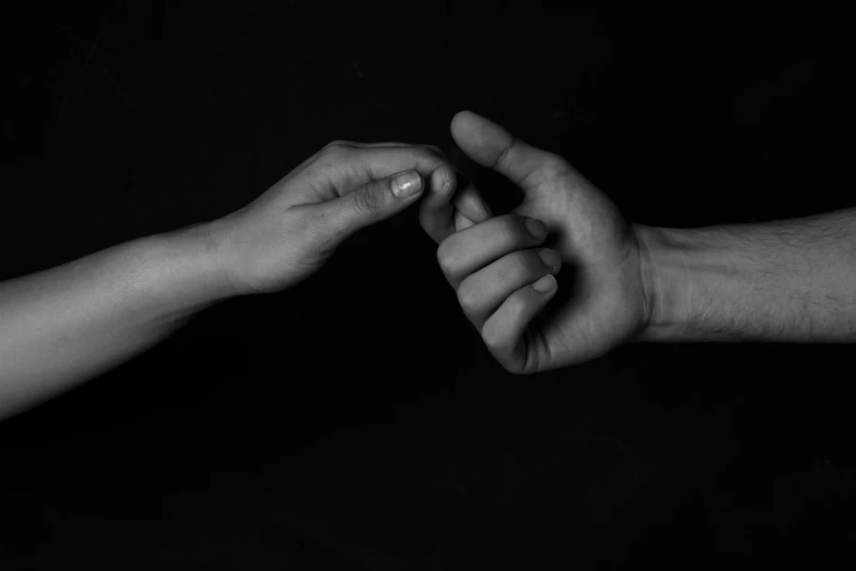 black and white pograph of two hands reaching towards each other