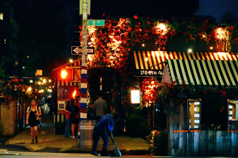 people are walking around a street with trees decorated with flowers