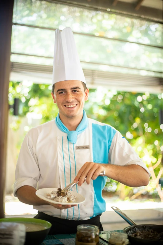 a male chef is smiling and putting food on a plate