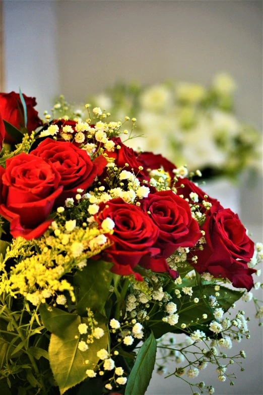 a vase with red roses in it sitting on a table