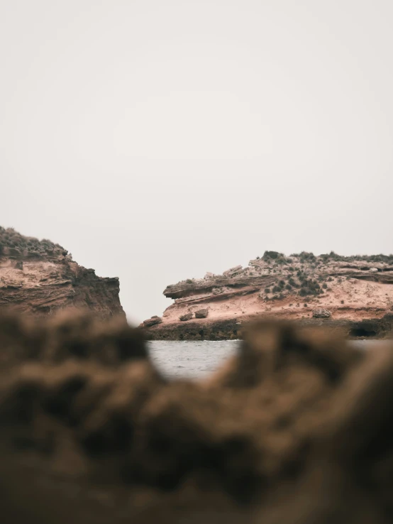 a rock formation by the water has a red face on it