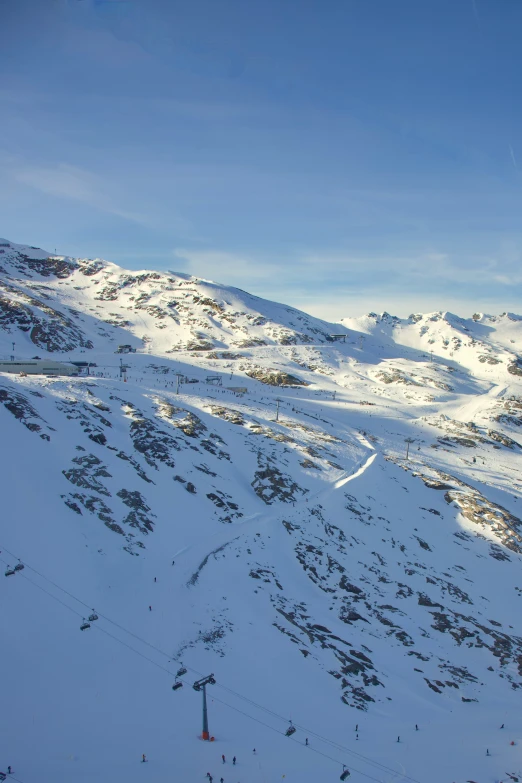 view from top of snow covered mountains of skiers on slope