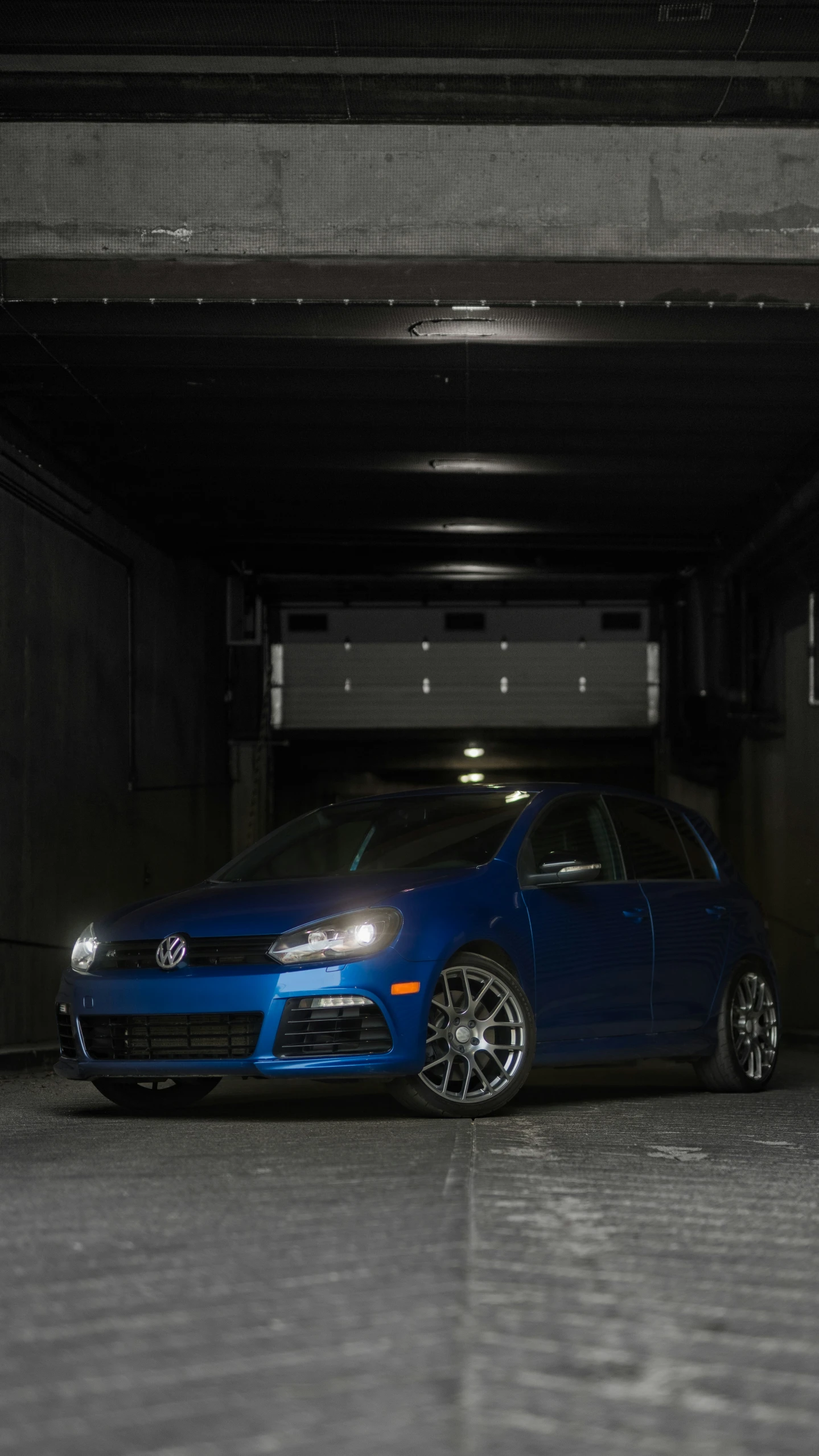 a blue volkswagen is parked in an underground parking lot