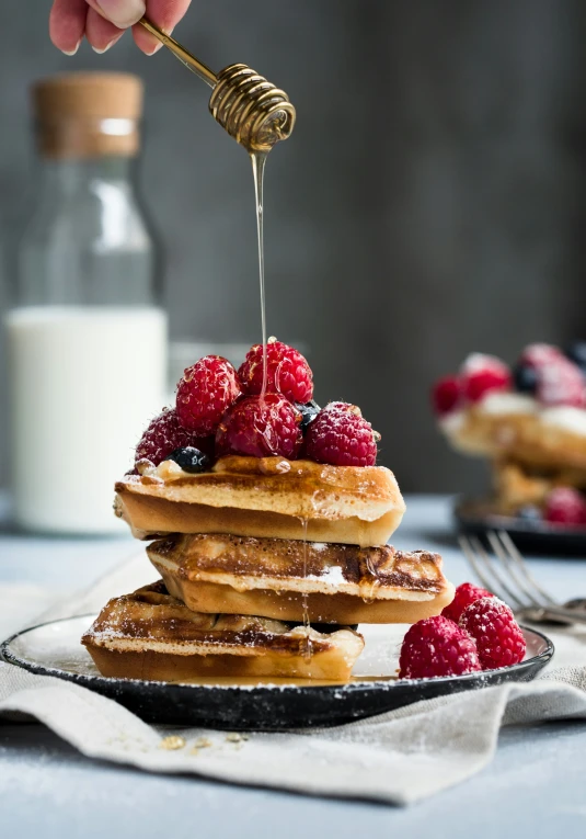 a person is drizzing maple syrup on some pancakes