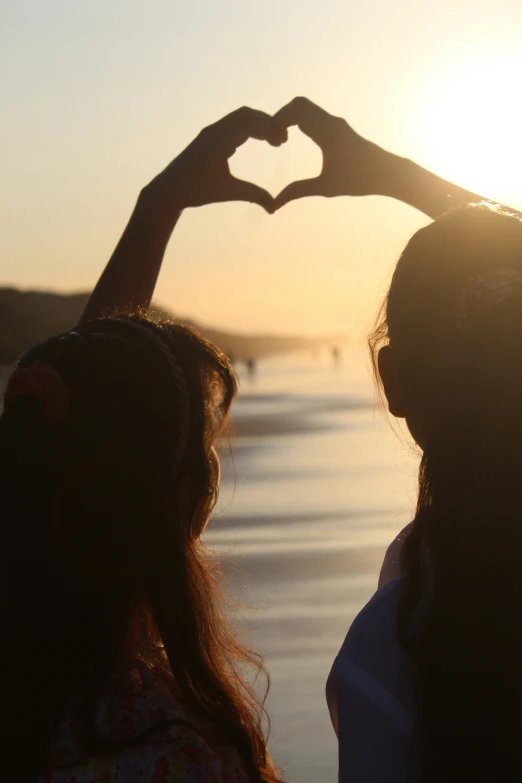 two women making the shape of a heart with their hands