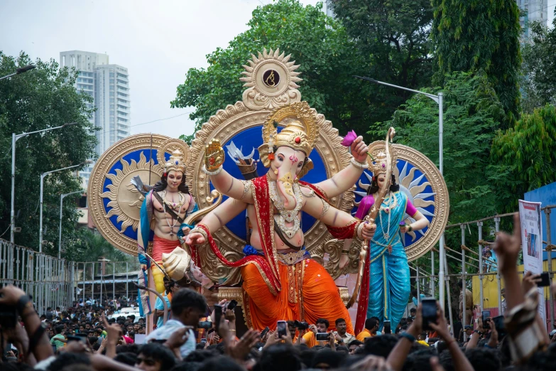 a group of people in a parade with floats and statues