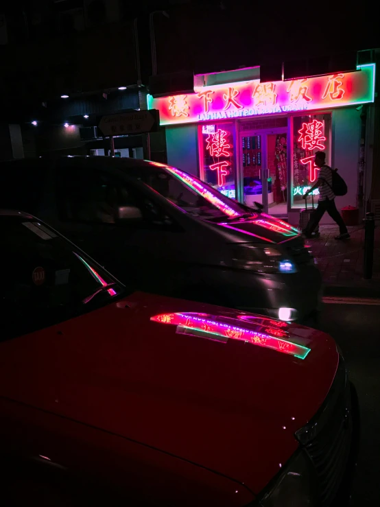 cars and neon lights in front of a bar on the street