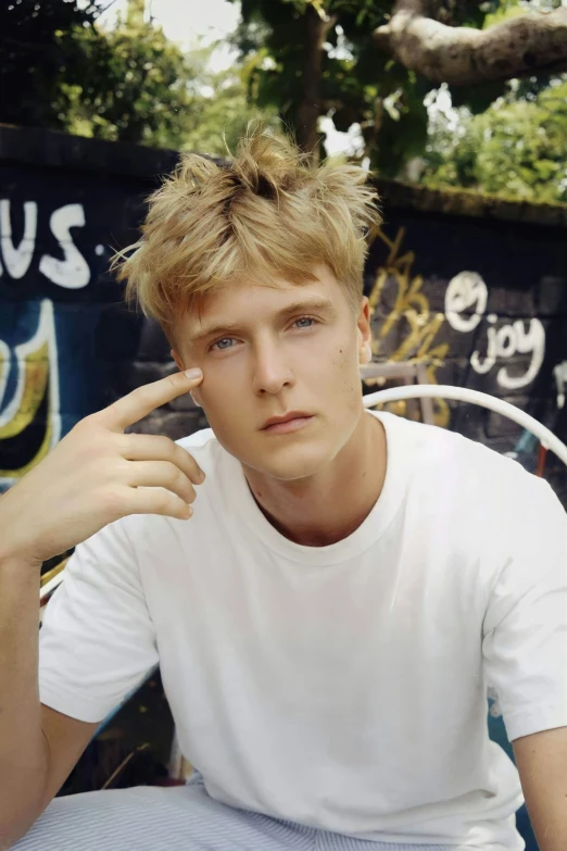 a young man sits in front of a painted wall